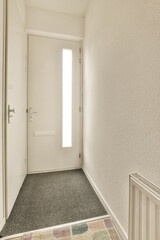an empty hallway with white walls and black carpeting, there is a door leading to the entrance into the room