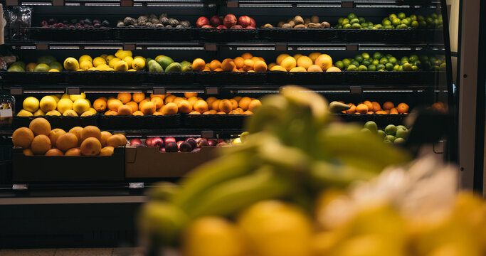 Rows of fresh and ripe sorted fruits placed in shelves under light