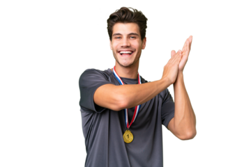 Young caucasian man with medals over isolated background applauding after presentation in a conference
