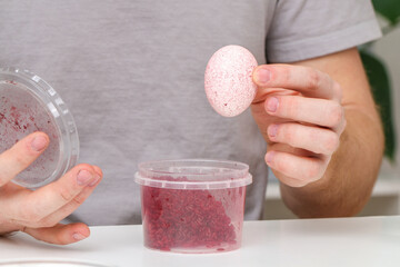 A man lays an egg and shakes a container of rice to color the egg. An unusual way of coloring and...