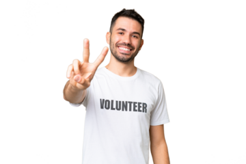 Young volunteer caucasian man over isolated chroma key background smiling and showing victory sign