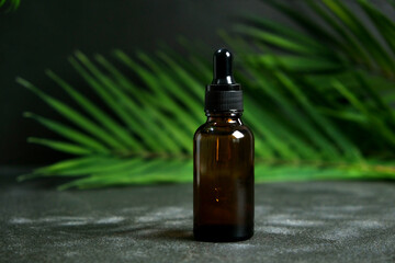 Drop of clear liquid, oil, serum or tincture dripping from pipette in the neck of a brown medical...