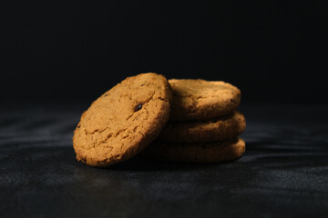 Oatmeal chocolate chip cookies. Cookies crumbs. Oatmeal cookies with chocolate on a black background with sunlight.