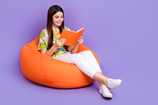 Full body photo of relaxing hobby teenager girl lying pouf read genre romantic book late summer nights isolated on violet color background