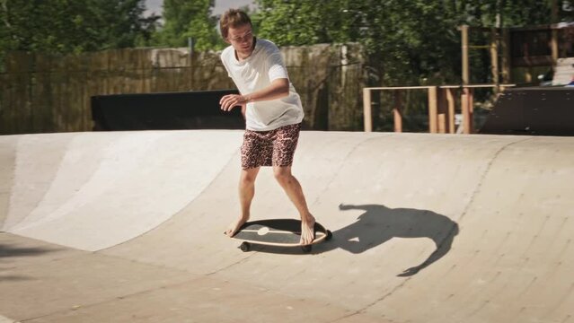 A cool guy rides in a skate park on a skate surf. A skilled young man is free to skateboard.