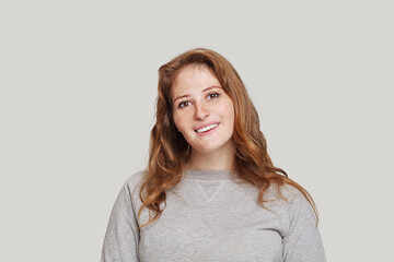 Obraz premium Attractive redhead model woman with healthy curly ginger hair smiling on white background