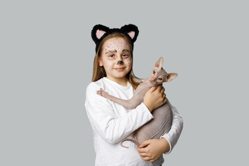 Young girl child painting kitten face holding cat pet on grey background
