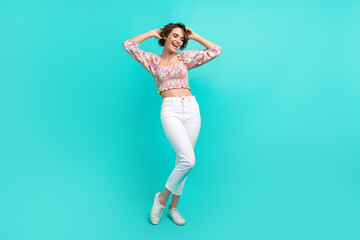 Fototapeta na wymiar Full length photo of cheerful optimistic cute girl dressed flower print blouse hold arms on head isolated on teal color background