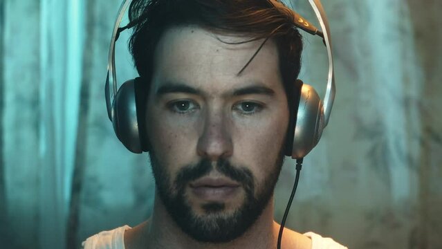 Male introvert wearing vintage silver headphones, screen glare on face, frontal