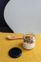 ドライフルーツ蜜がかかった瓶に入ったオーバーナイトオーツと木のスプーンのテーブルシーン