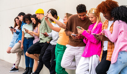 Obraz premium Happy playful multiethnic group of young friends bonding outdoors - Multiracial millennials students meeting in the city, concepts of youth, people lifestyle, diversity, teenage and urban life