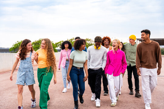 Happy playful multiethnic group of young friends bonding outdoors - Multiracial millennials students meeting in the city, concepts of youth, people lifestyle, diversity, teenage and urban life