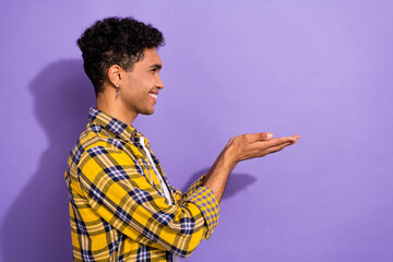 Photo of positive cheerful guy wear plaid yellow shirt holding arms empty space isolated violet color background