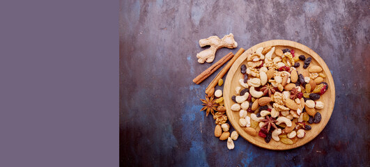 Aesthetic wooden bowl with assorted nuts, raisins and cranberries from above. Hazelnuts , Walnuts, almonds, cashews. Healthy snacks and desserts. Extra wide banner. Copy space