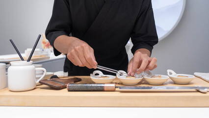 Professional chef preparing and cooking raw fresh fish ingredient on the table with knife for...