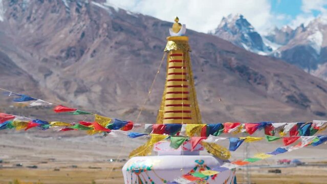 Closeup shot of prayer flags in front of stupa overlooking the snow covered mountain range at Sani Monastery near Padum in Zanskar Valley, Ladakh, India. Stupa in front of the snowy Himalayas. 