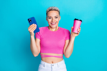 Photo portrait of lovely young lady excited raise hold device paper cup dressed stylish pink garment isolated on cyan color background