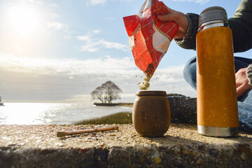 closeup of unrecognizable person sitting on the pier preparing mate in the morning.