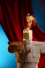 A scented candle smokes on a Roman column against a painted curtain on a blue background