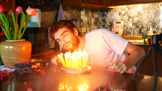 A 36-year-old man lights candles on a cake. Makes a wish to blow candles, but they won't blow out