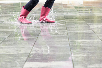 Fototapeta na wymiar Happy woman with boots splashing in a rain puddle