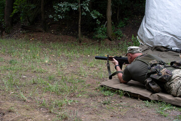 A Ukrainian soldier trains in shooting from a machine gun in a prone position