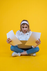 Bored young blonde business woman, student sit floor legs crossed hold papers documents using laptop feeling bored young blonde business woman. Confused, pensive thinking searching of problem solution