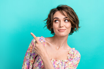 Portrait of cute good mood girl with bob hairdo dressed flower print blouse look directing empty space isolated on teal color background