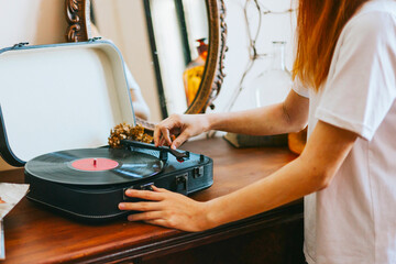 A modern teenage girl with dyed hair turns on a retro record player, meeting modern with retro