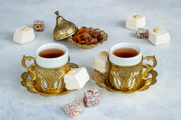 Obraz na płótnie Canvas Hot tea in cups in Arabic or Turkish style with sweets and nuts