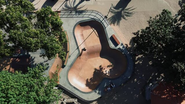 A teenager rides alone in a bowl of a skatepark. Tricks in the skate park from a young talented rider. Aerial view of a skater performing tricks in the pool.