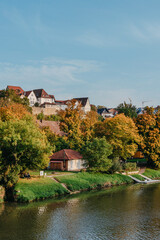 Naklejka na ściany i meble Autumn Landscape - River And Shores With Trees, Bushes And City Houses Marbach Am Neckar. Panoramic Aerial View Of The River In A City Park. Deciduous Trees, Golden Leaves. Autumn Landscape. Ecology
