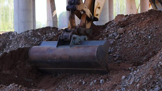 The excavator digs and loads the earth into the bucket, moving the soil to another place. The concept of heavy machinery. Excavator bucket close up.