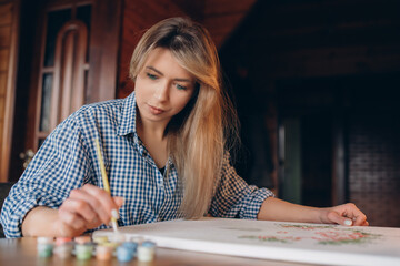 Fototapeta premium A young woman is painting a picture. The background is blurred. Art concept.
