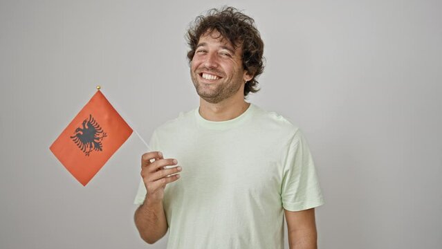 Young hispanic man smiling confident holding albanian flag over isolated white background