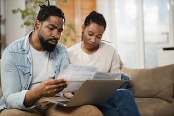 Worried African American couple going through their financial bills at home