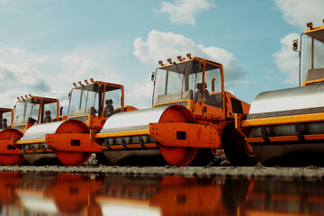 An endless row of yellow big road rollers standing in the row. Heavy machines.
