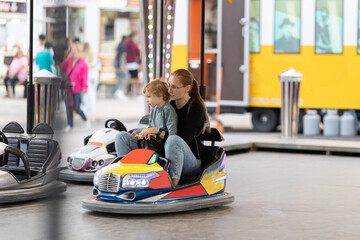 Angry mom scolds her son sitting in the dodgem