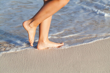 Barefoot legs of a girl walking the sandy beach, close up