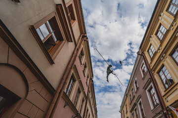 
Tenement houses in Lublin, a rope and a man walking on it. - obrazy, fototapety, plakaty