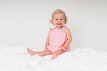 Fototapeta premium Smiling baby girl sitting on white fabric