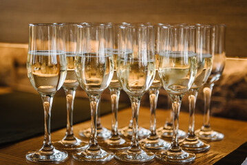 Glasses of champagne on table bar. Many glass of white wine. Buffet. Celebration of birthday, baptism, wedding or corporate party. Catering service. Serves glasses of sparkling wine. Closeup.