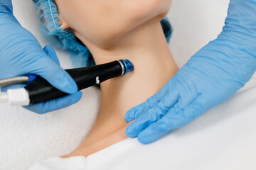 Naklejka premium Facial skin care machine in spa clinic for anti-aging or acne treatment. The concept of aesthetic medicine, beauty tools, latest technologies in beauty industry.