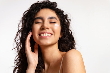 Laughing young woman with a drop of cream on her cheek enjoying clear glowing skin