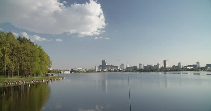 Minsk, Belarus. Reservoir Drozdy. Time Lapse View On Forest, Public Park And City On Background. People Resting Walking At Riverside In Summer Day. City Pond And Park. Concept Of Rest And Weekends.