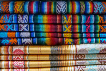 Close up of brightly colored folded traditional fabric for sale at Otavalo market in Ecuador