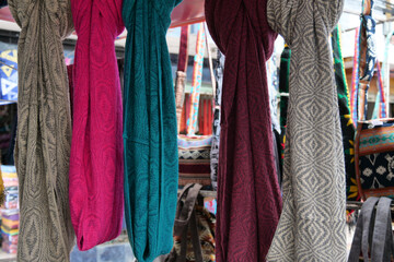 Colourful scarves woven from alpaca wool hanging from rod at Otavalo market, Ecuador