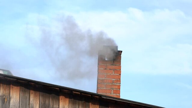 Black smoke billows from the brick chimney 