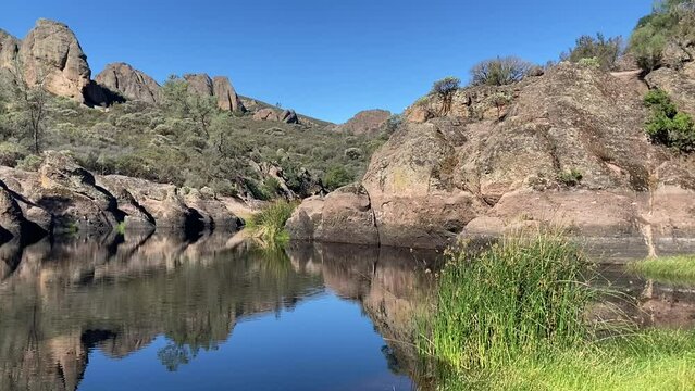 The beautiful and tranquil Bear Gulch Reservoir surrounded by stunning red rock formations in Pinnacles National Park. Taken on a sunny, blue sky day in summer - California, USA