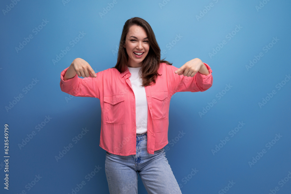 Sticker smart brunette lady casual style pointing finger at space for information on studio background